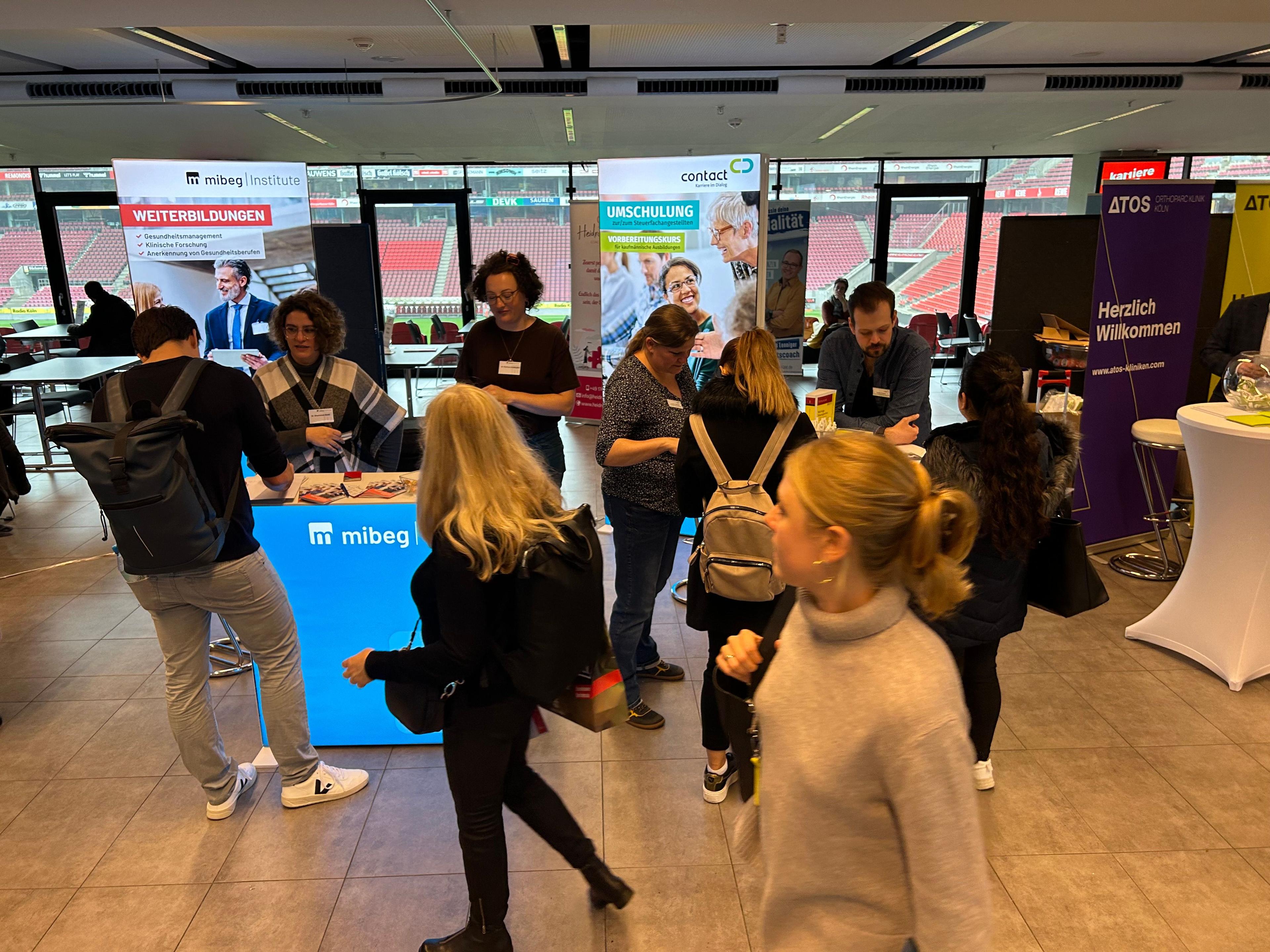 Stand der mibeg Gruppe auf einer Messe mit Teilnehmern im Vordergrund