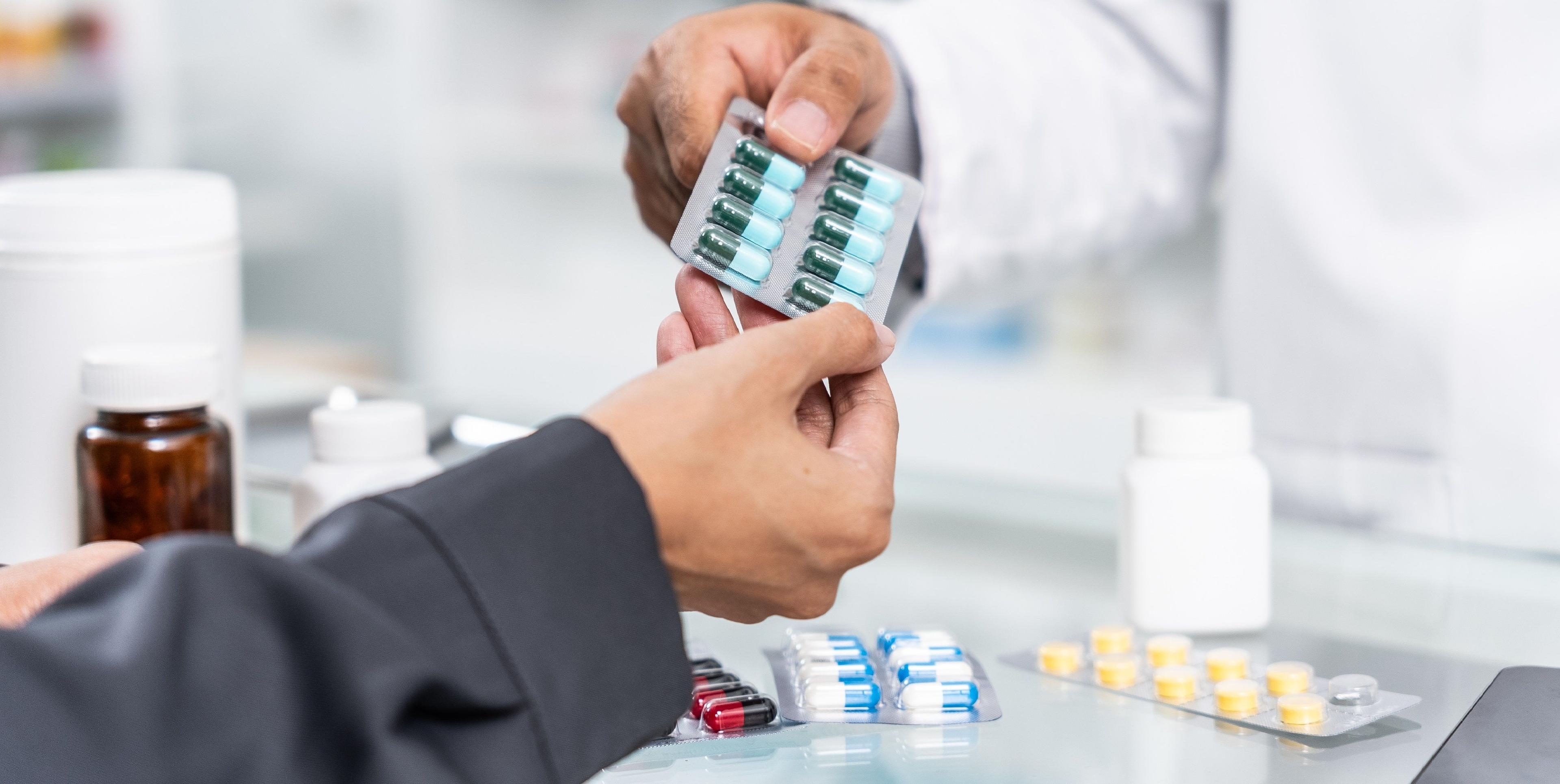 Apotheker übergibt einem Kunden Medikamente