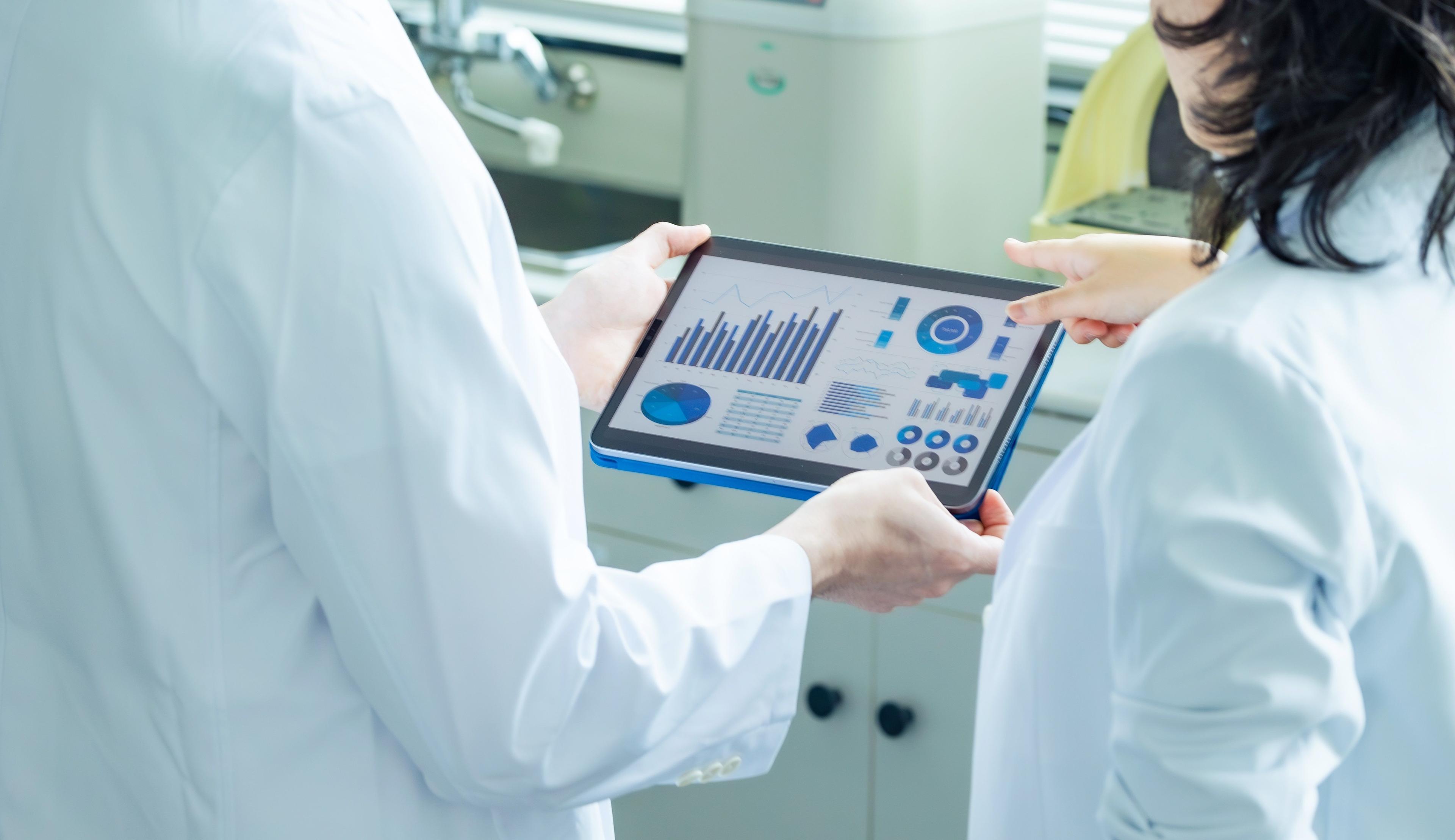 Zwei Mitarbeiter in der klinischen Forschung schauen sich eine Auswertung auf einem Tablet an