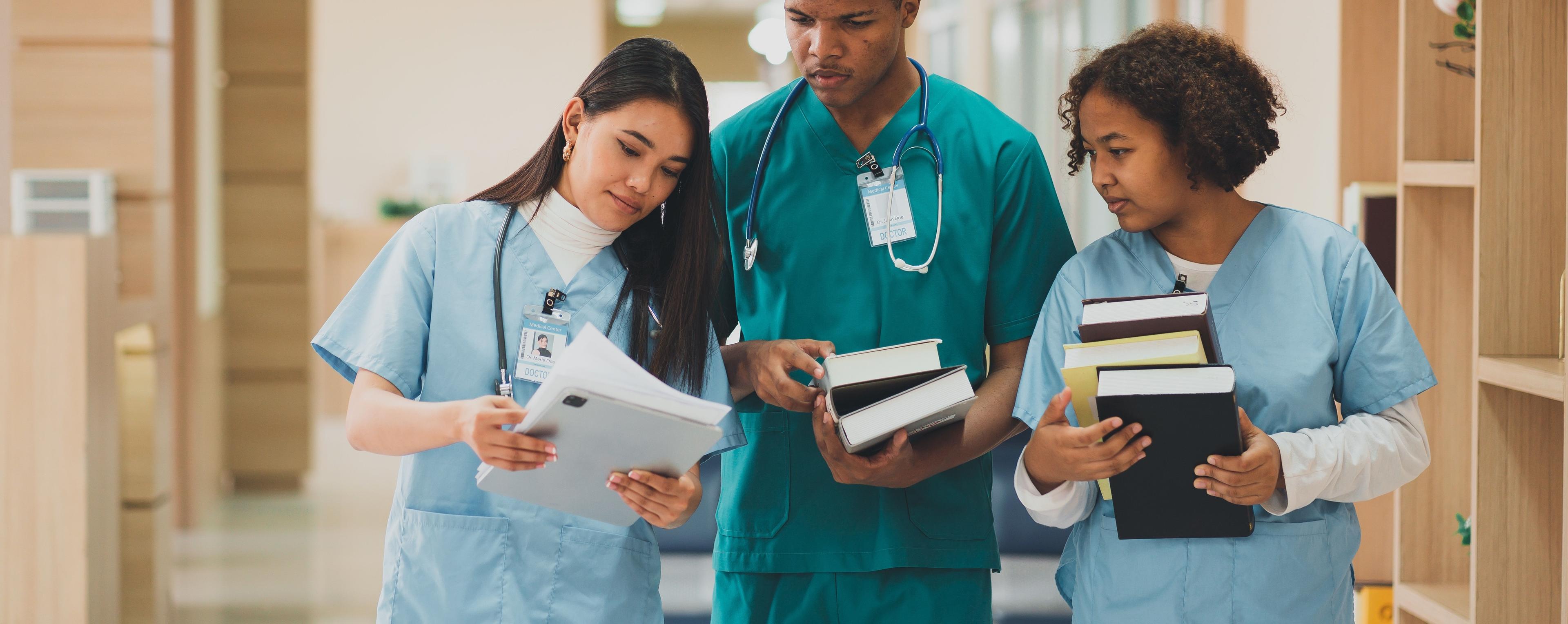 Mitarbeiter eines Krankenhauses schauen auf einem Flur im Krankenhaus in Ihre Unterlagen zur Qualifizierung in der klinischen Praxis